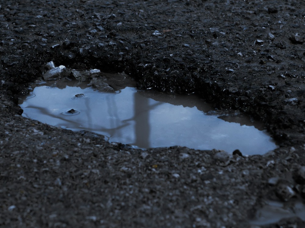 A water-filled pothole in a road