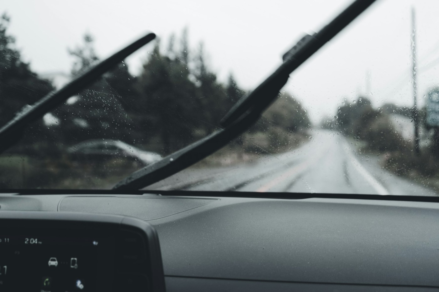 A wiper blade on a windshield on a grey, wet day